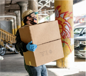 Man wearing mask and gloves carries boxes