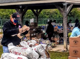 Volunteers deliver food and produce to members of the Central American immigrant community in northern Hamilton County, Ohio, under an outdoor pavilion