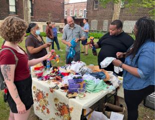 Group of adults upcycling with fabric on a table outside 