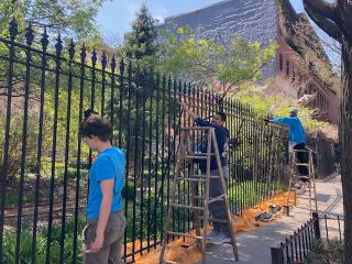 Two teen interns painting a public fence