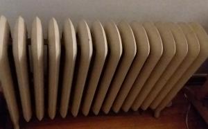 Cream colored home radiator against white wall.