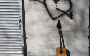 An orange acoustic guitar lying against a white brick wall