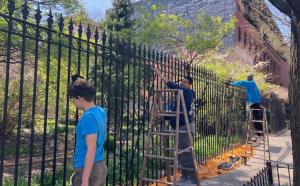 Two teen interns painting a public fence